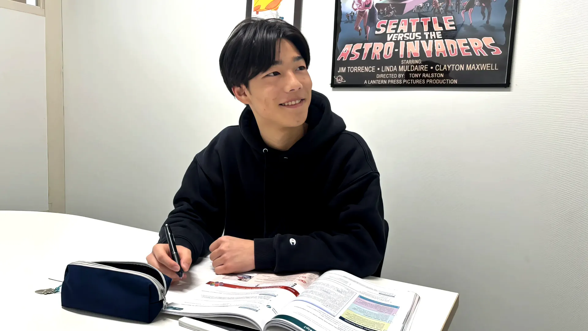 AIE国際高等学校神戸キャンパスで、英語の教科書を広げて笑顔で学習に取り組む男子生徒。