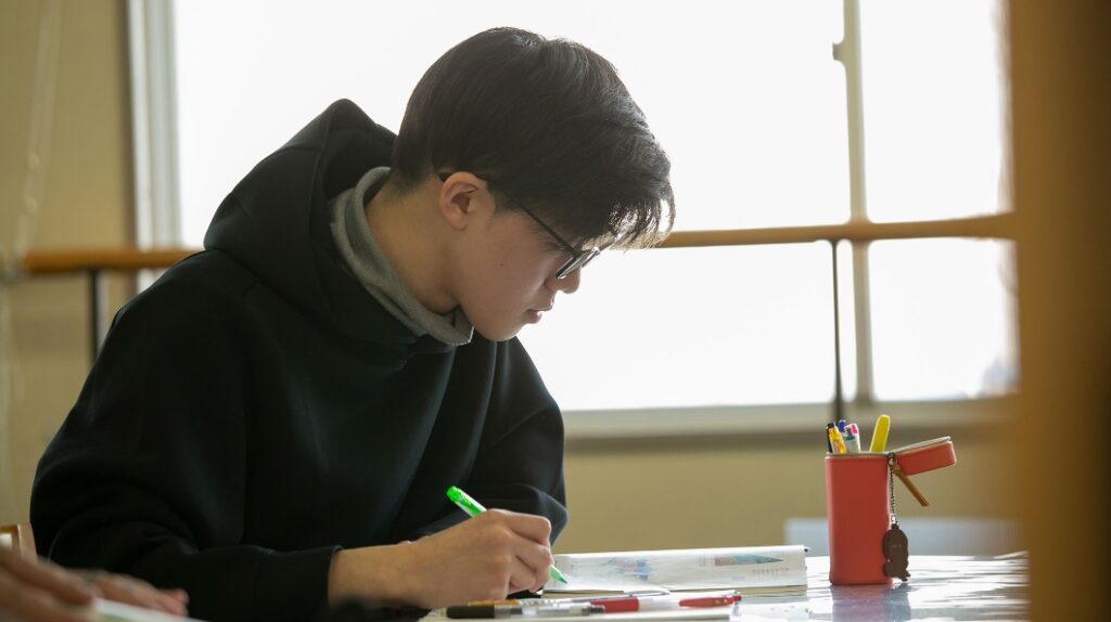 AIE国際高等学校 神戸キャンパスの明るい教室で、集中して学習に取り組む生徒の様子。